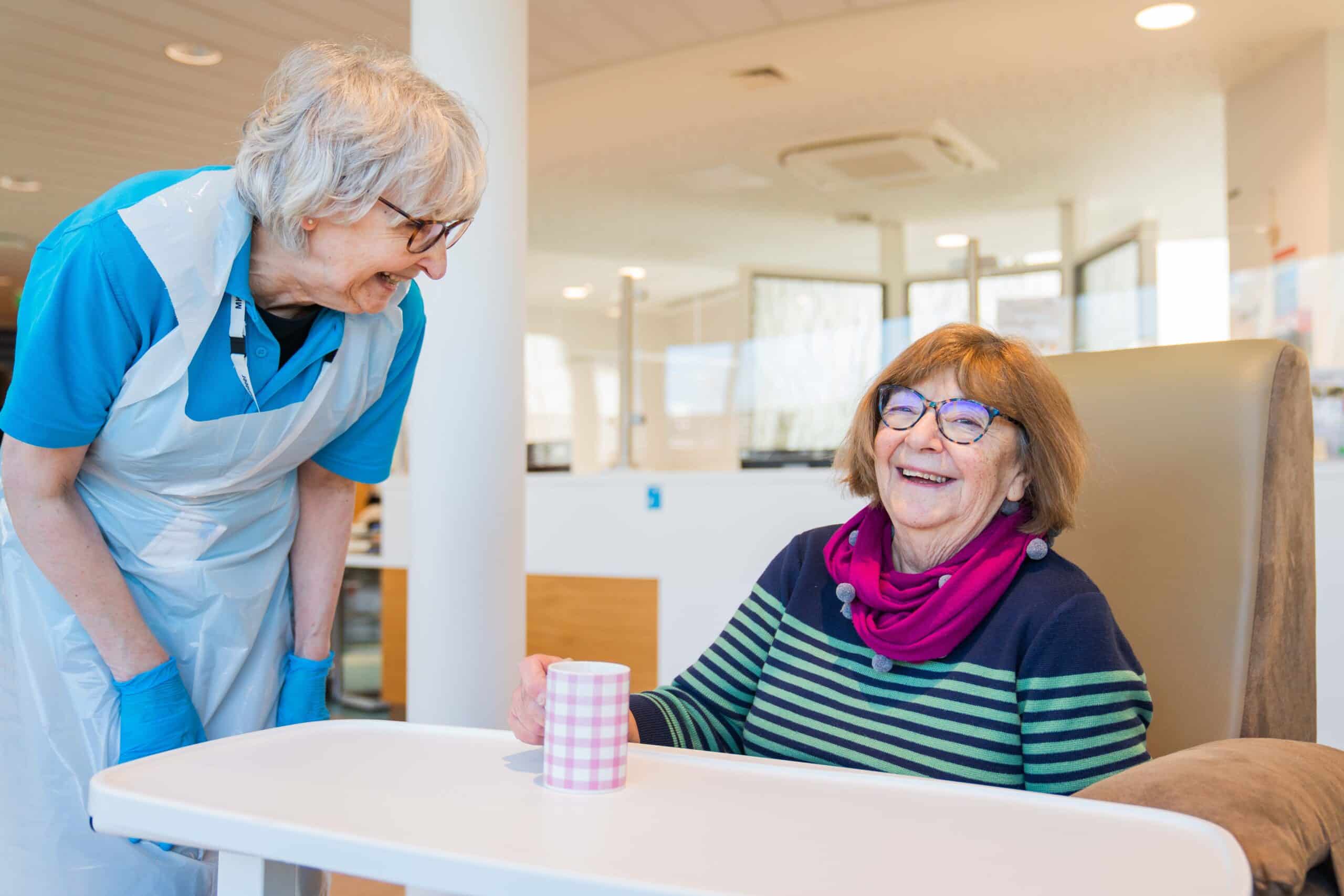 A hospital volunteer and a female patient laughing together